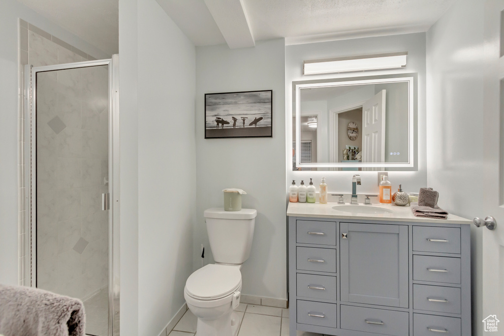 Bathroom featuring baseboards, toilet, tile patterned floors, vanity, and a shower stall