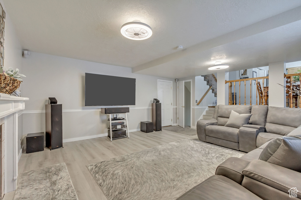 Living area with baseboards, wood finished floors, stairs, a textured ceiling, and a fireplace