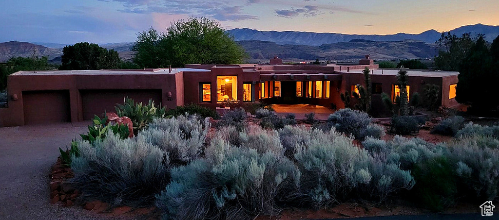Back of house featuring a mountain view, a chimney, an attached garage, and stucco siding