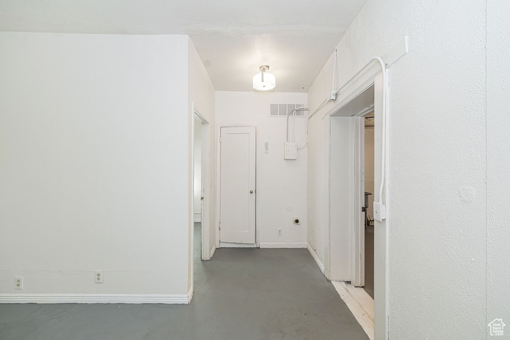 Corridor featuring concrete flooring, visible vents, and baseboards