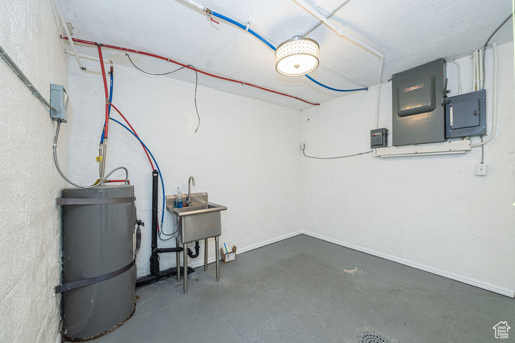 Below grade area featuring electric panel, water heater, and a sink