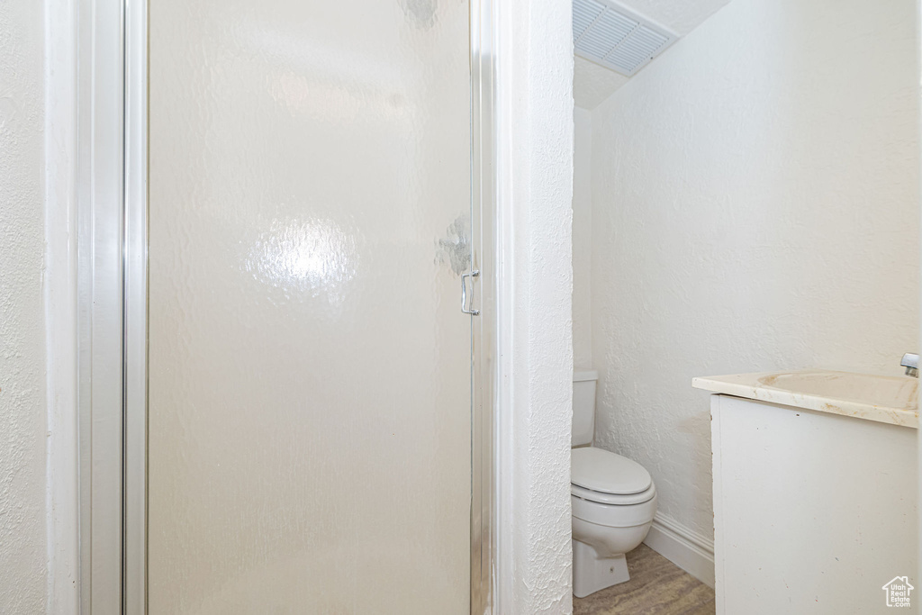 Bathroom featuring a stall shower, visible vents, a textured wall, toilet, and vanity