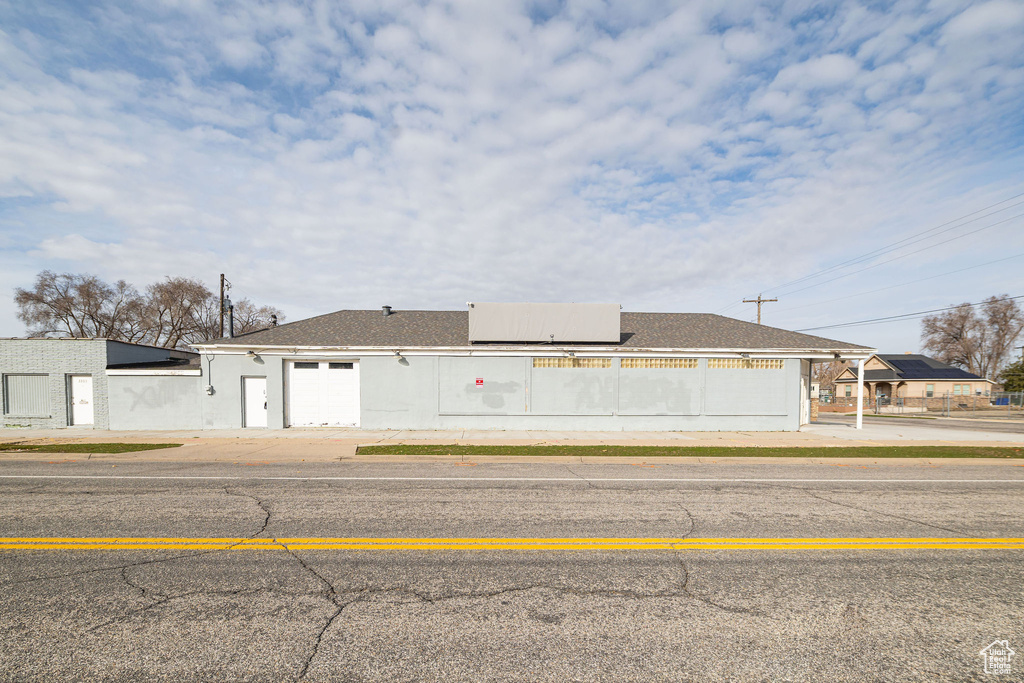 View of front of house with a shingled roof, fence, and stucco siding