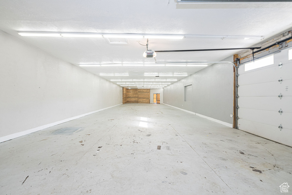 Garage featuring a garage door opener and baseboards