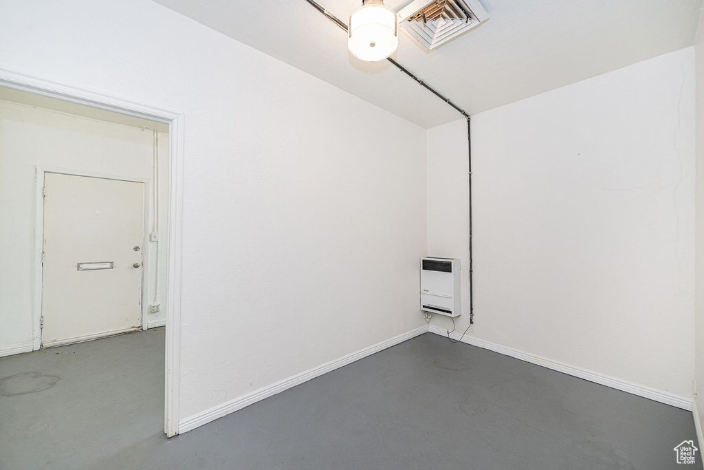 Spare room featuring baseboards, heating unit, and finished concrete floors