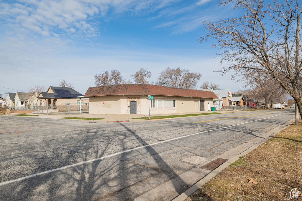 View of front of house featuring uncovered parking, a residential view, fence, and stucco siding