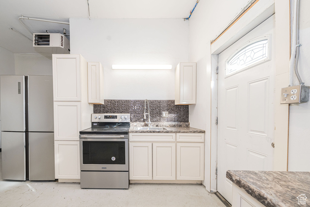Kitchen with dark stone counters, stainless steel appliances, tasteful backsplash, and a sink