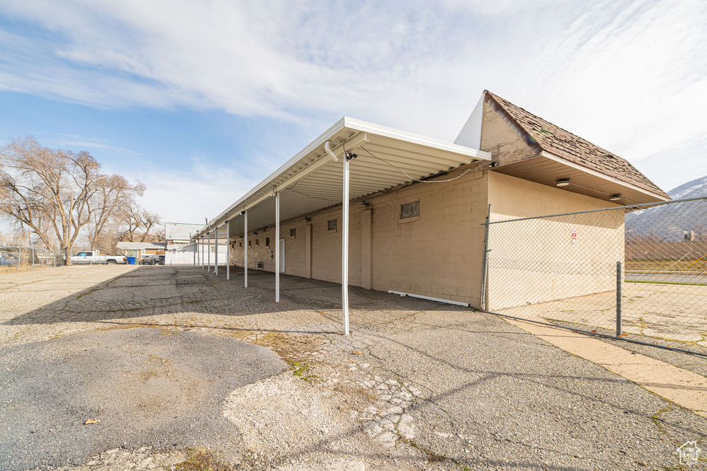 View of home's exterior with an attached carport, concrete block siding, and fence