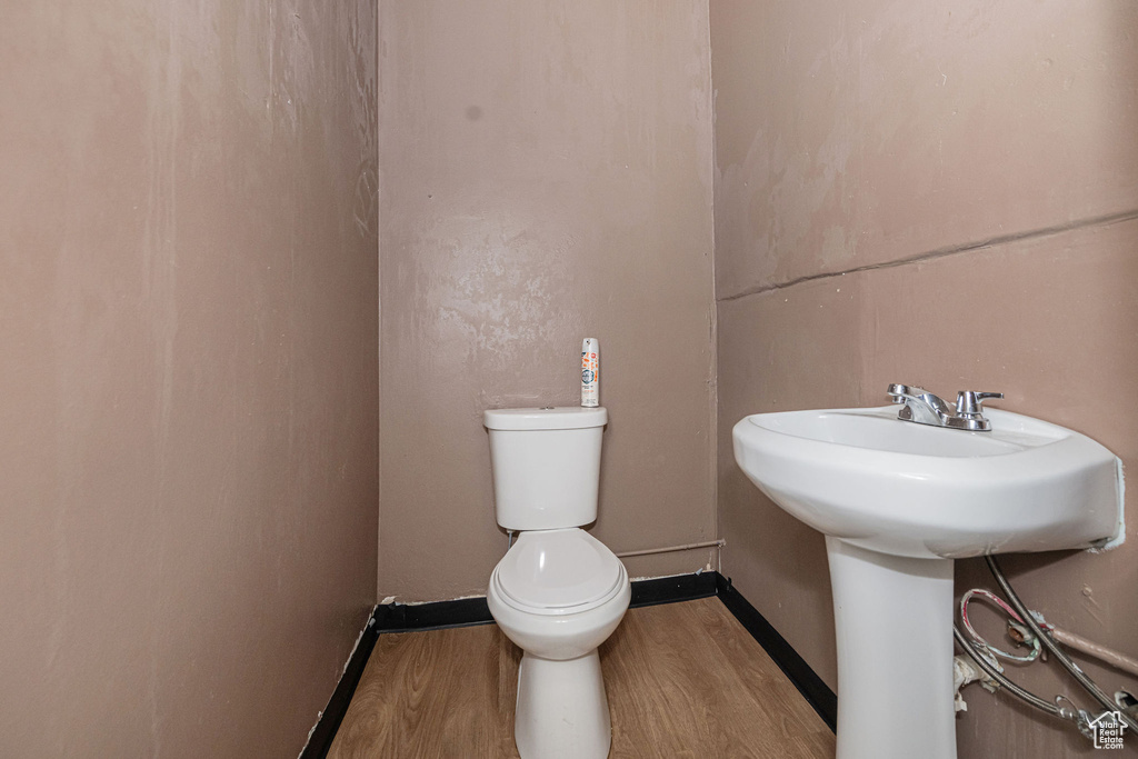 Half bath with toilet, baseboards, and wood finished floors