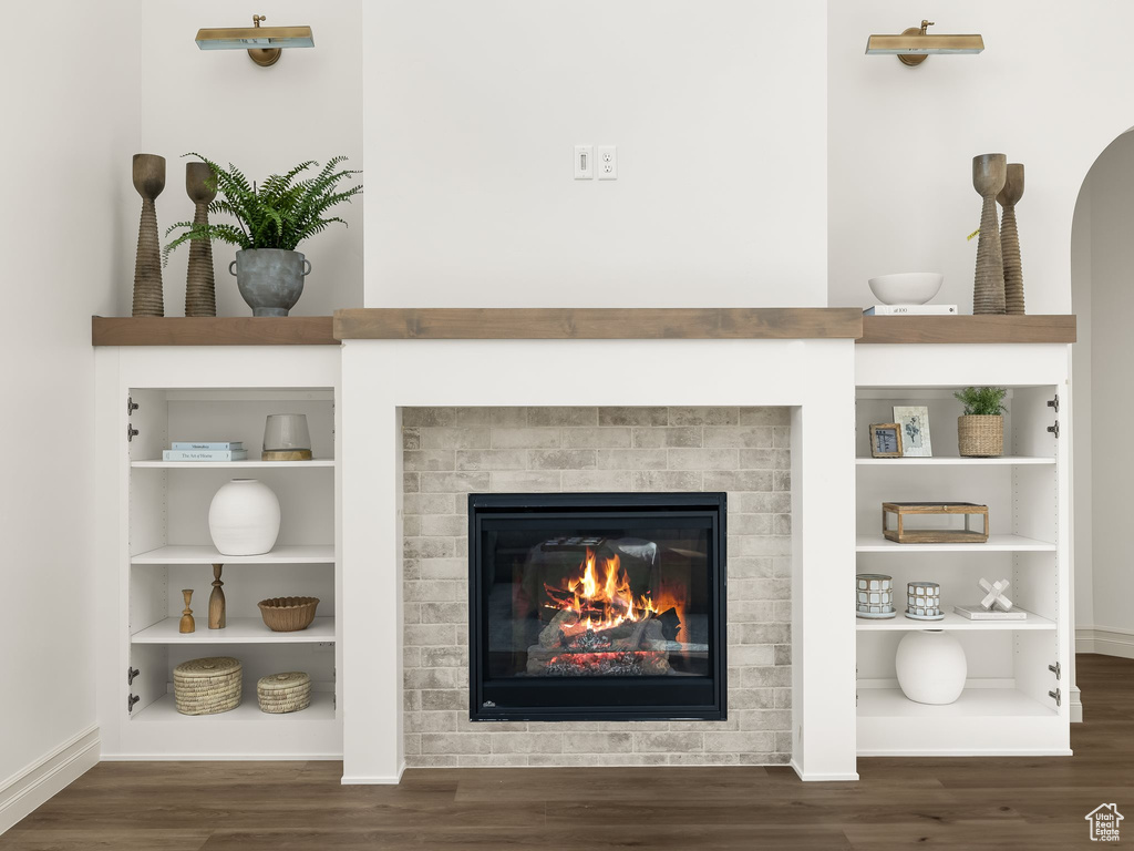 Interior details with built in shelves, a fireplace, baseboards, and wood finished floors