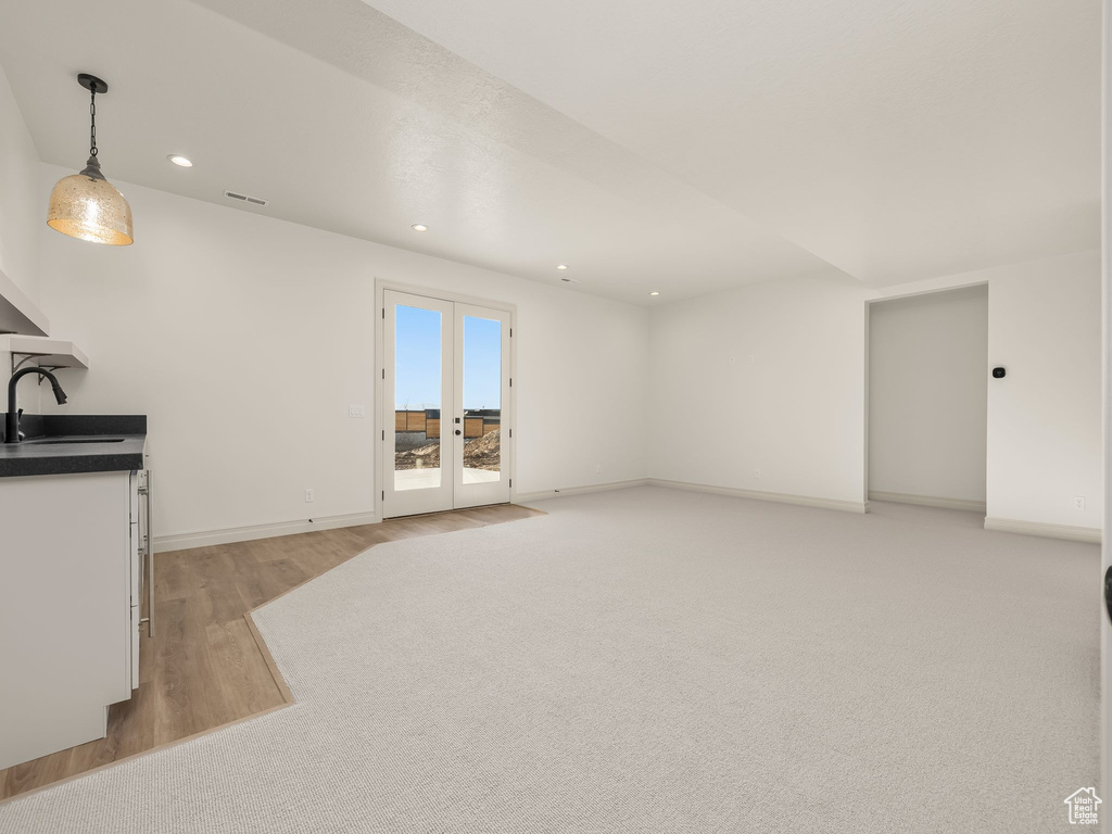 Unfurnished living room with recessed lighting, a sink, baseboards, french doors, and light wood-type flooring