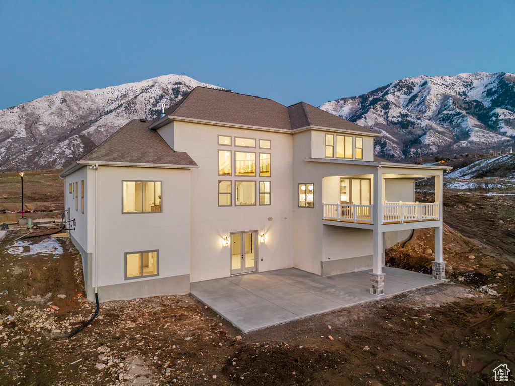 Rear view of house featuring stucco siding, a mountain view, a patio, and french doors