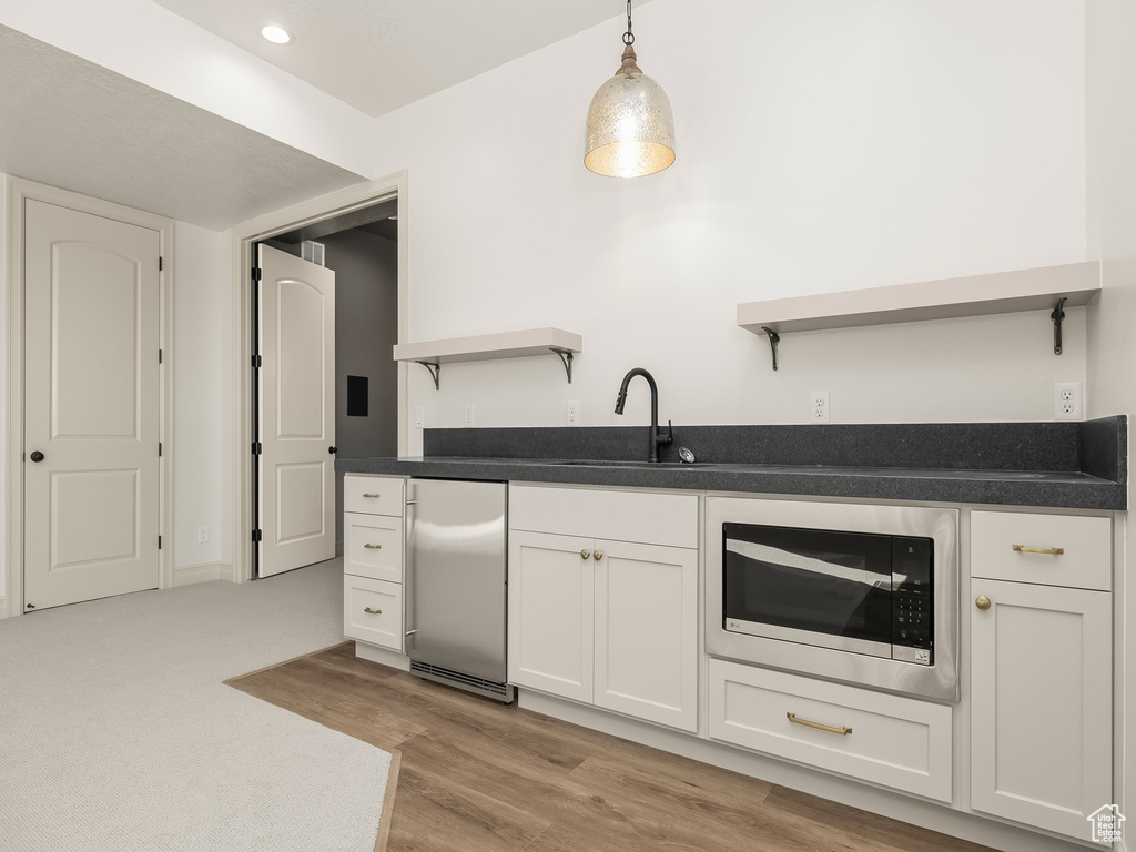 Kitchen featuring a sink, white cabinetry, appliances with stainless steel finishes, open shelves, and decorative light fixtures