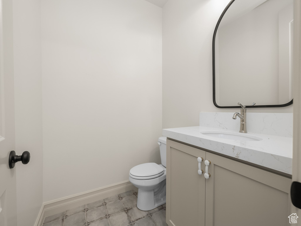 Half bath featuring toilet, baseboards, and vanity