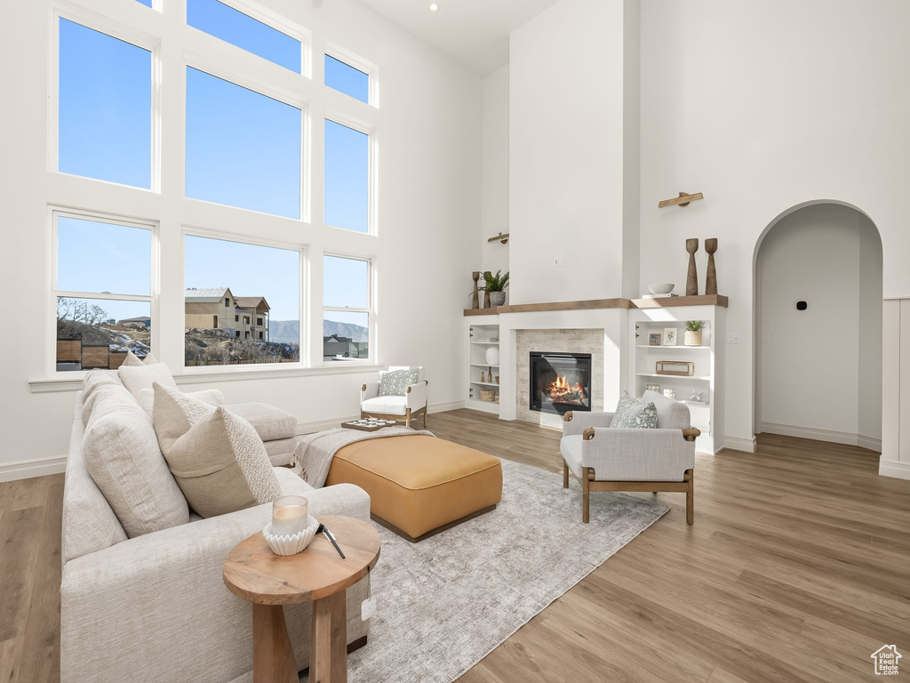 Living area featuring arched walkways, a fireplace, light wood-style flooring, and baseboards