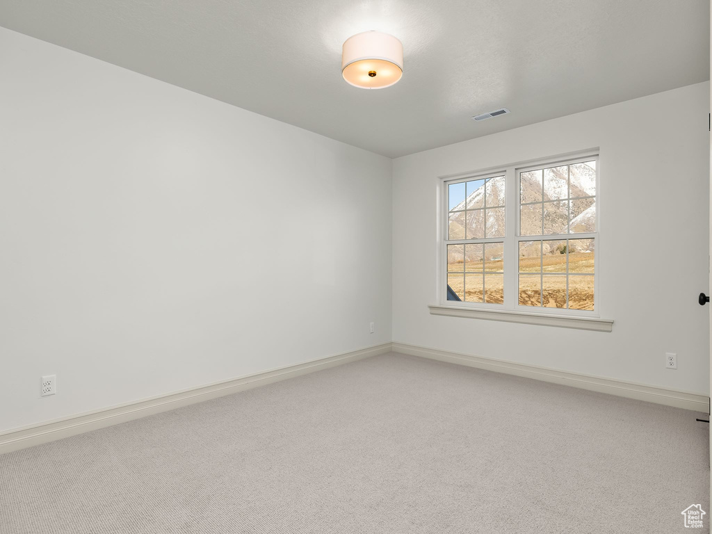 Empty room with carpet, visible vents, and baseboards