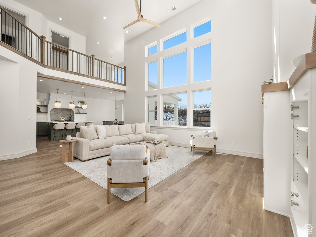 Living area with recessed lighting, a high ceiling, wood finished floors, visible vents, and baseboards