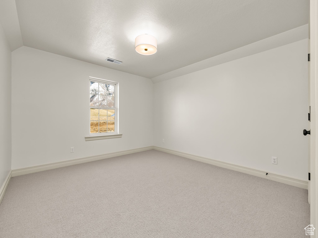 Spare room with baseboards, visible vents, and light colored carpet