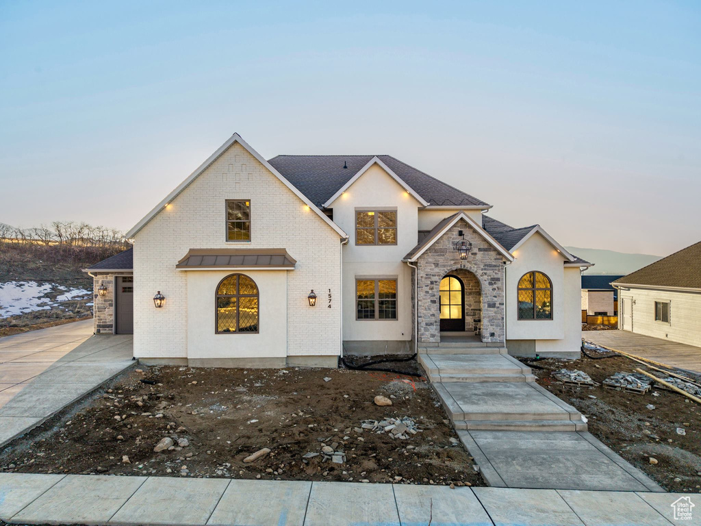 View of front of property with driveway and stone siding