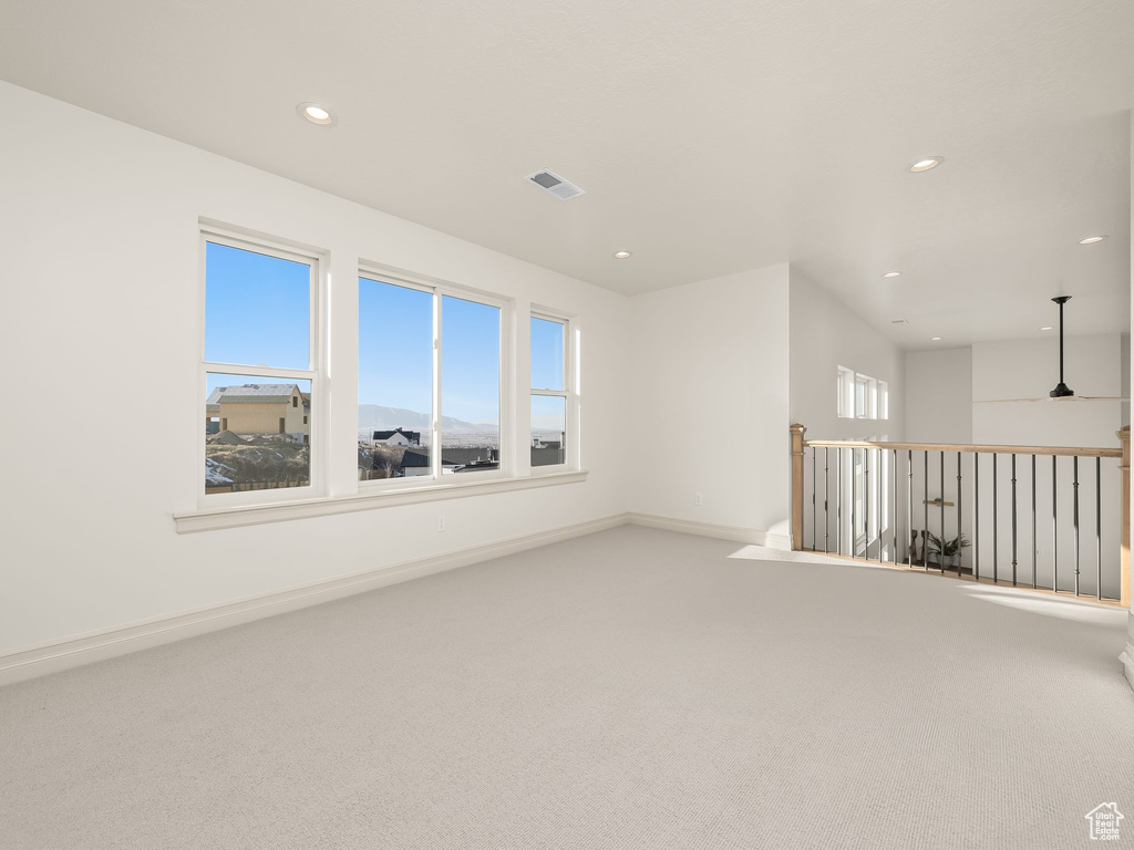 Carpeted spare room featuring a healthy amount of sunlight, baseboards, visible vents, and recessed lighting