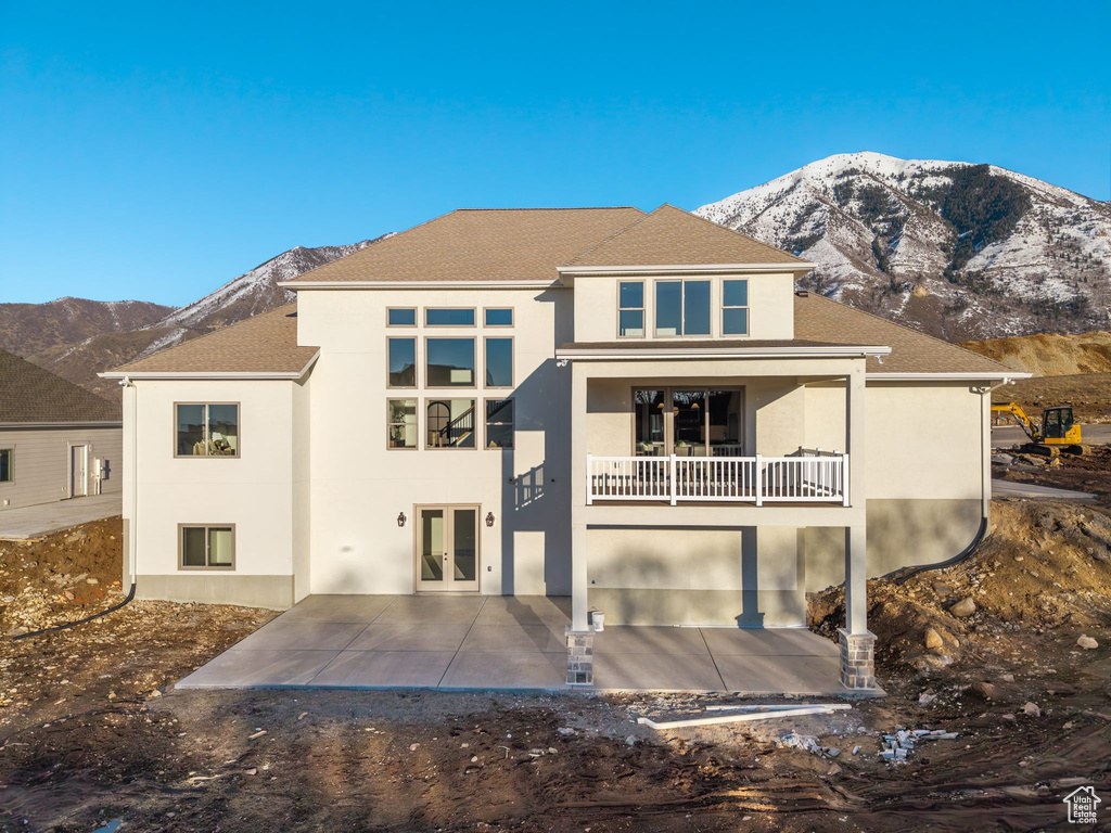 Back of house featuring a balcony, french doors, a patio area, a mountain view, and stucco siding