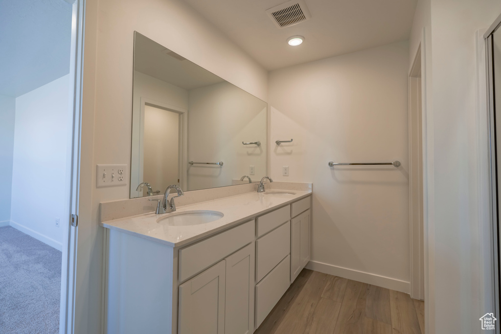 Full bathroom with double vanity, visible vents, baseboards, and a sink