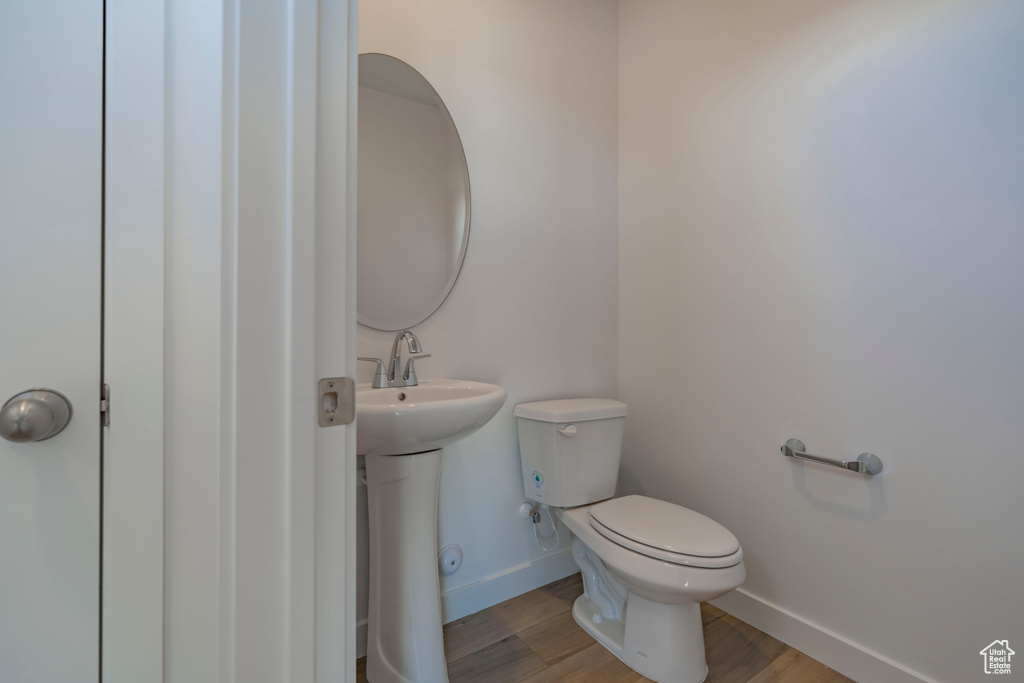 Half bathroom with a sink, baseboards, toilet, and wood finished floors
