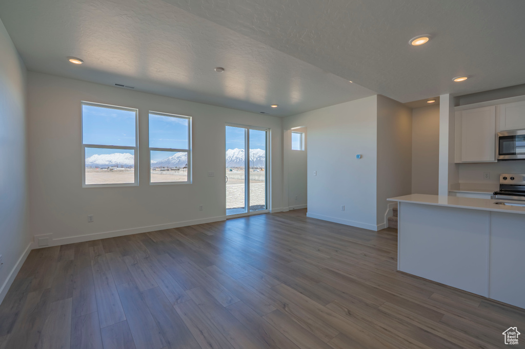 Kitchen featuring dark wood-type flooring, white cabinetry, appliances with stainless steel finishes, light countertops, and baseboards
