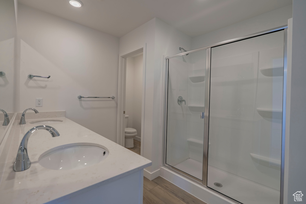 Full bathroom with wood finished floors, a stall shower, toilet, and a sink