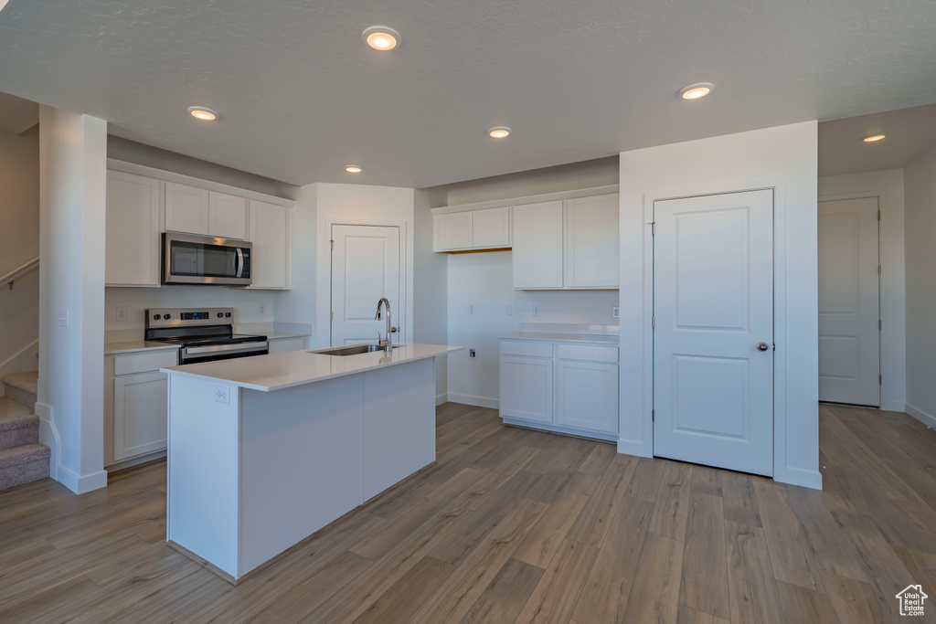 Kitchen featuring a sink, white cabinets, light wood-style floors, and stainless steel appliances
