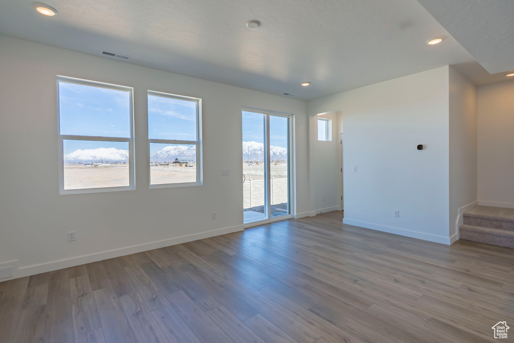 Unfurnished room featuring stairway, wood finished floors, visible vents, baseboards, and recessed lighting