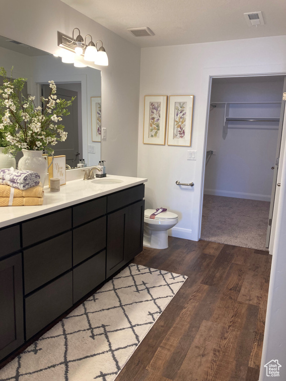 Full bath featuring toilet, visible vents, wood finished floors, and vanity