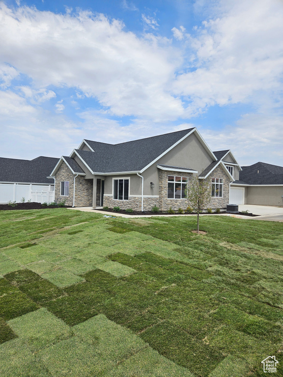View of front facade with stone siding, a front lawn, fence, and stucco siding