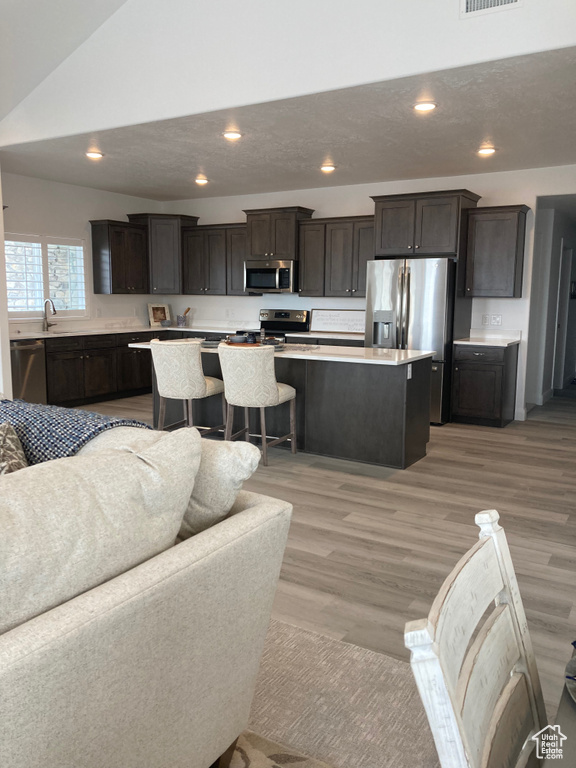 Living area featuring visible vents, lofted ceiling, a textured ceiling, light wood-type flooring, and recessed lighting