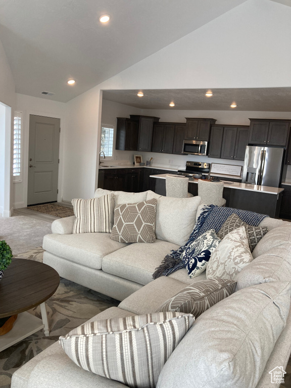 Living room featuring light colored carpet, baseboards, vaulted ceiling, and recessed lighting