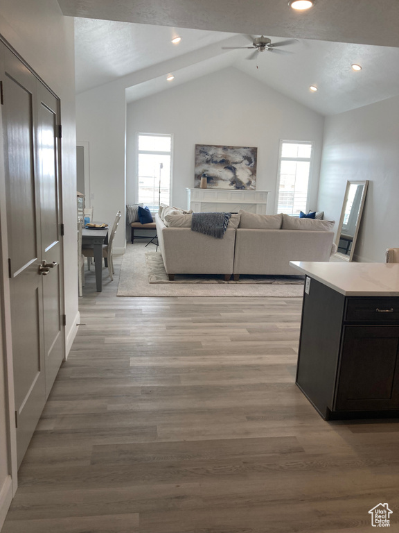 Living area with lofted ceiling, plenty of natural light, light wood finished floors, and recessed lighting