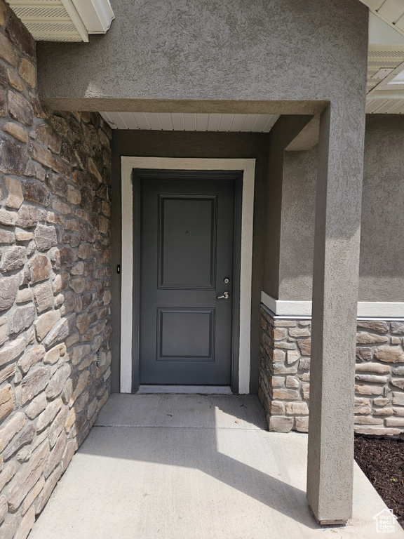 View of exterior entry featuring stone siding and stucco siding