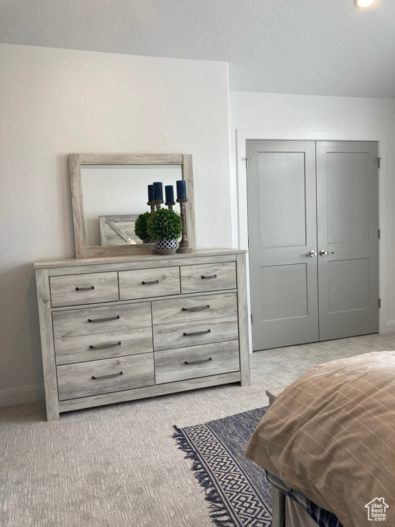 Bedroom with baseboards, a closet, a textured ceiling, and light colored carpet