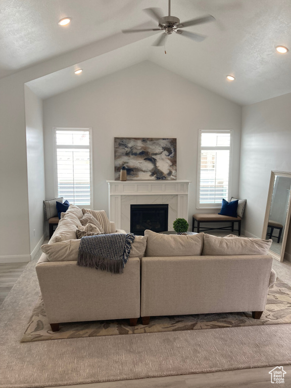Living area with a high end fireplace, a healthy amount of sunlight, and lofted ceiling