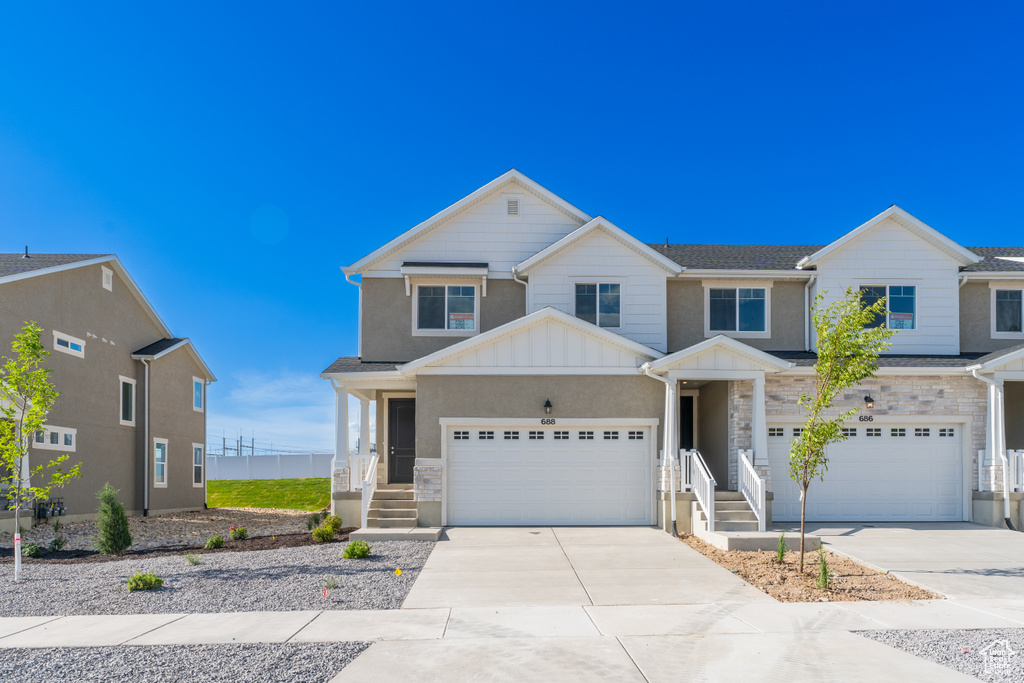 View of front of property featuring stone siding, driveway, board and batten siding, and an attached garage