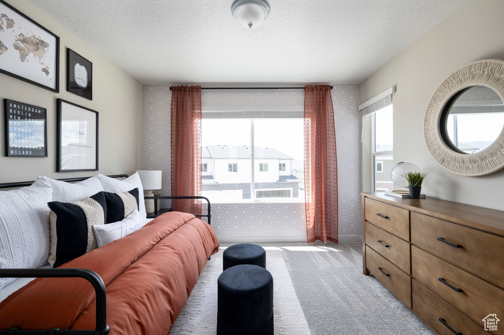 Bedroom featuring wallpapered walls, a textured ceiling, and light colored carpet