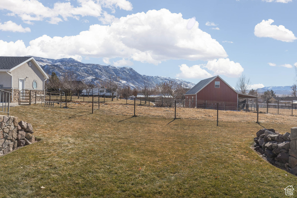 View of yard featuring a pole building, fence, an outdoor structure, and a mountain view