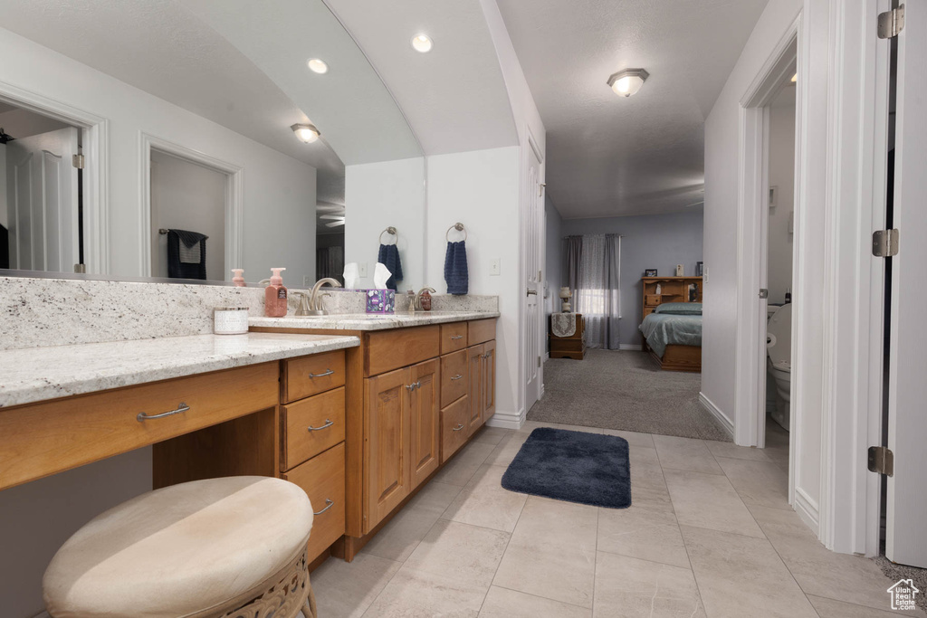 Ensuite bathroom featuring toilet, ensuite bathroom, vanity, baseboards, and tile patterned floors