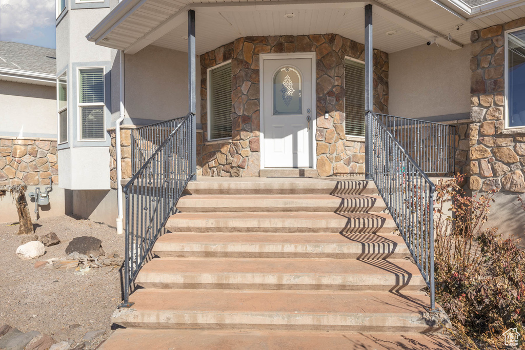 Property entrance featuring stone siding, covered porch, and stucco siding