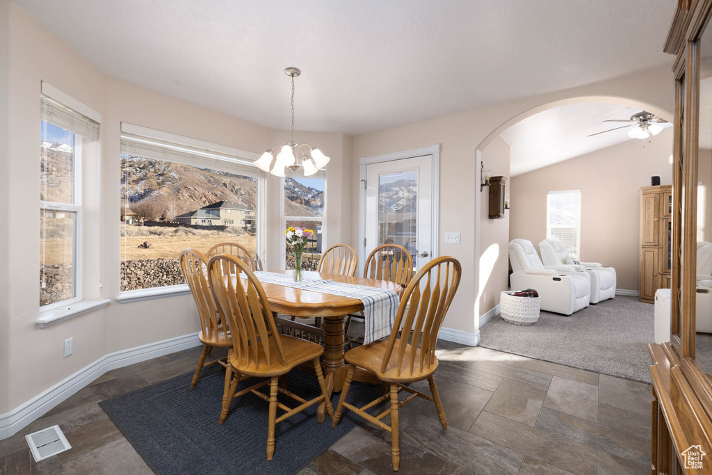 Dining room featuring arched walkways, lofted ceiling, visible vents, and baseboards