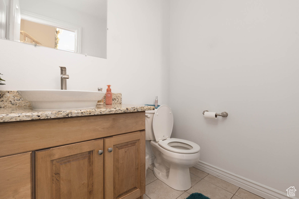 Bathroom featuring toilet, tile patterned flooring, baseboards, and vanity