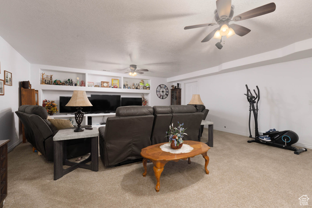 Living area with light carpet, ceiling fan, a textured ceiling, and baseboards