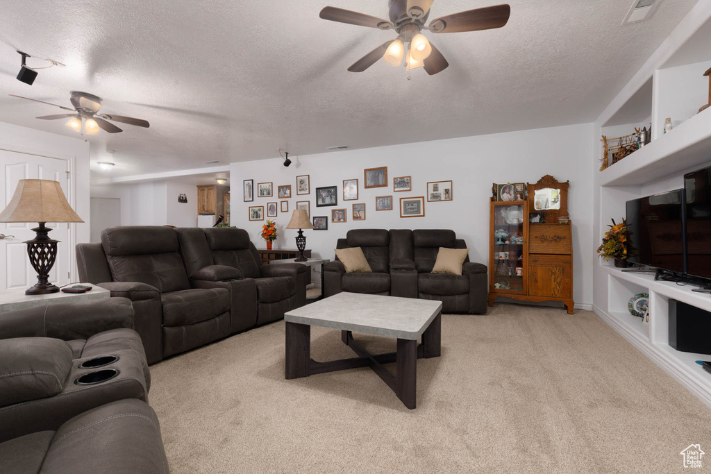 Living room featuring built in shelves, visible vents, light colored carpet, a ceiling fan, and a textured ceiling