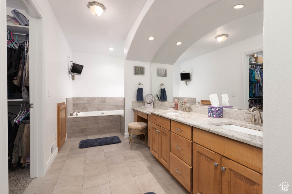 Full bathroom with a garden tub, double vanity, tile patterned flooring, and a sink