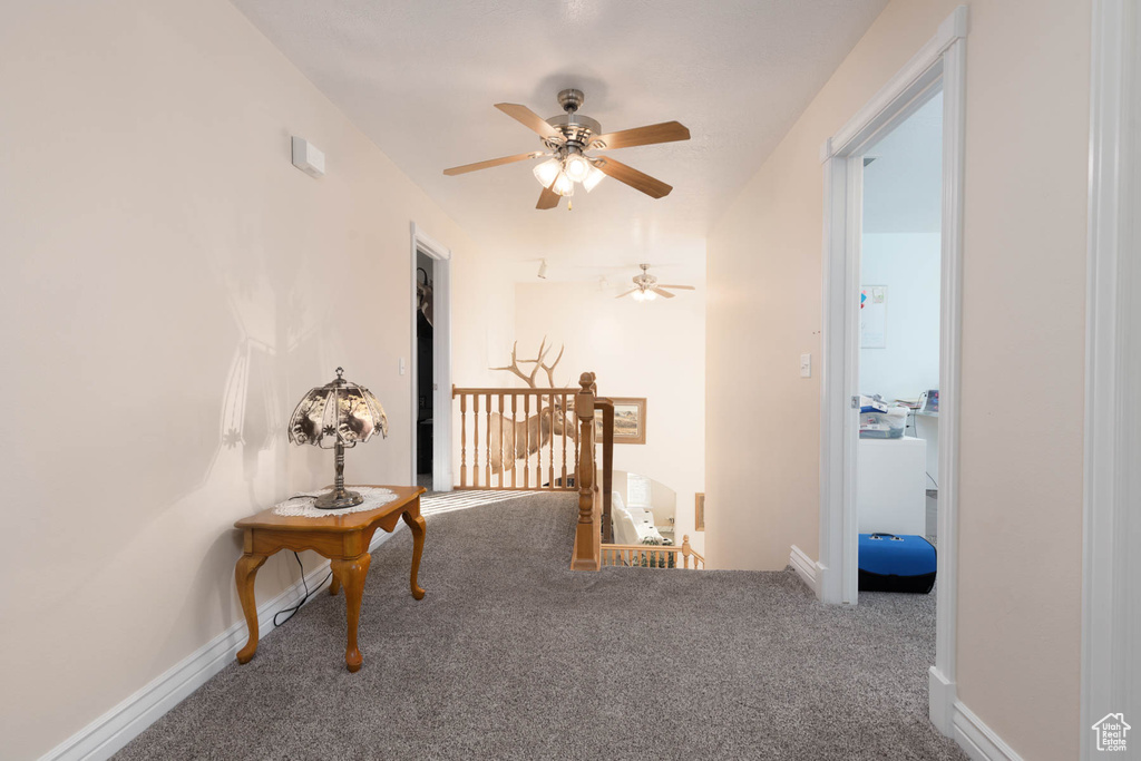 Hallway featuring carpet floors, baseboards, and an upstairs landing